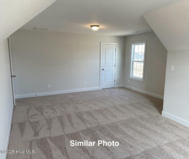 bonus room featuring light carpet and a textured ceiling