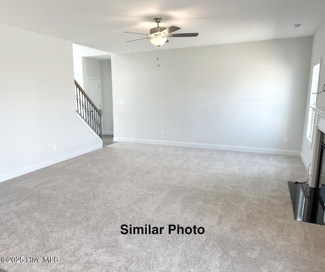 unfurnished living room with ceiling fan and carpet