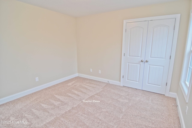 unfurnished bedroom with light colored carpet and a closet