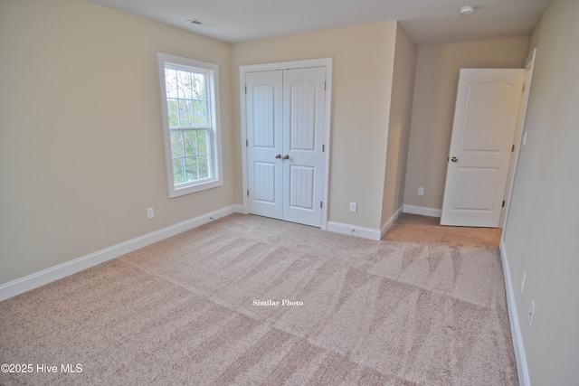 unfurnished bedroom featuring light colored carpet and a closet