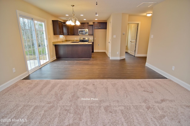 kitchen with pendant lighting, dark colored carpet, a notable chandelier, kitchen peninsula, and stainless steel appliances