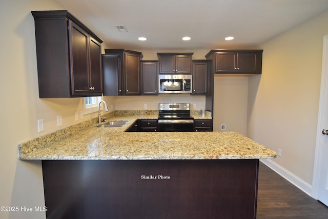 kitchen with light stone countertops, appliances with stainless steel finishes, sink, and kitchen peninsula