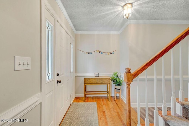 entryway featuring ornamental molding, a textured ceiling, and light hardwood / wood-style floors