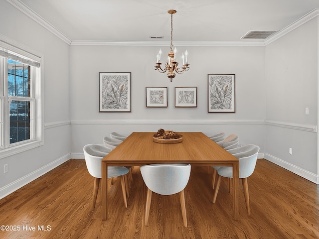 dining area featuring wood-type flooring, ornamental molding, and a chandelier