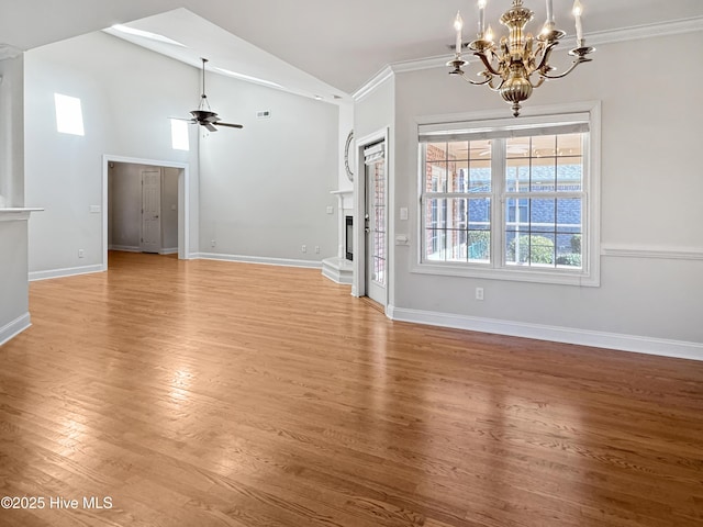 unfurnished living room featuring lofted ceiling, hardwood / wood-style flooring, ceiling fan with notable chandelier, and crown molding