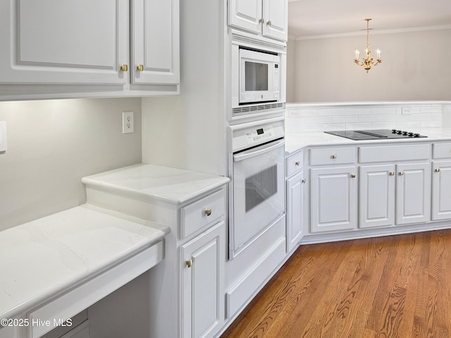 kitchen with an inviting chandelier, white appliances, decorative light fixtures, and white cabinets