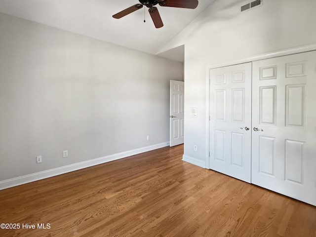 unfurnished bedroom with hardwood / wood-style floors, vaulted ceiling, a closet, and ceiling fan