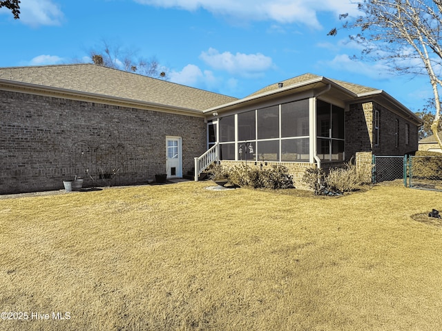 rear view of property featuring a lawn and a sunroom