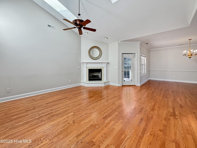 unfurnished living room with crown molding, light hardwood / wood-style flooring, a skylight, high vaulted ceiling, and ceiling fan with notable chandelier