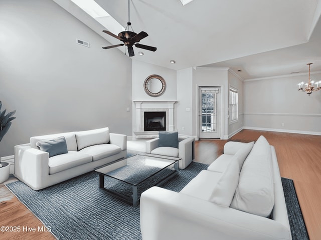 living room with ceiling fan with notable chandelier, ornamental molding, high vaulted ceiling, and hardwood / wood-style floors