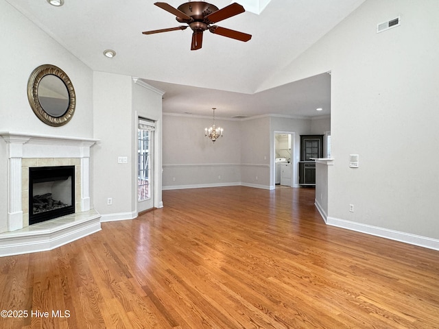 unfurnished living room with hardwood / wood-style flooring, vaulted ceiling, ceiling fan with notable chandelier, and a fireplace