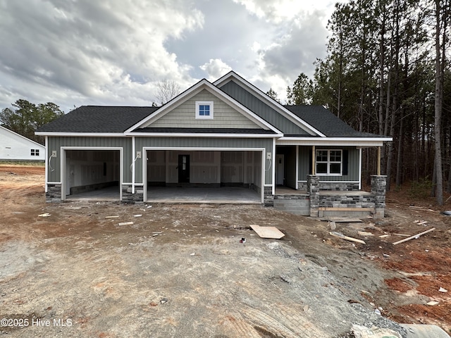 view of front of property with an attached garage, covered porch, a shingled roof, dirt driveway, and board and batten siding