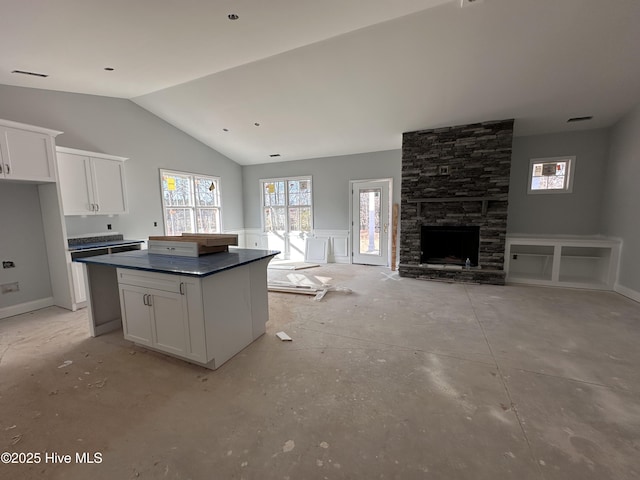 kitchen featuring lofted ceiling, a center island, white cabinets, and dark countertops