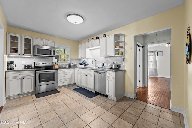 kitchen with white cabinetry, appliances with stainless steel finishes, light tile patterned flooring, and decorative backsplash