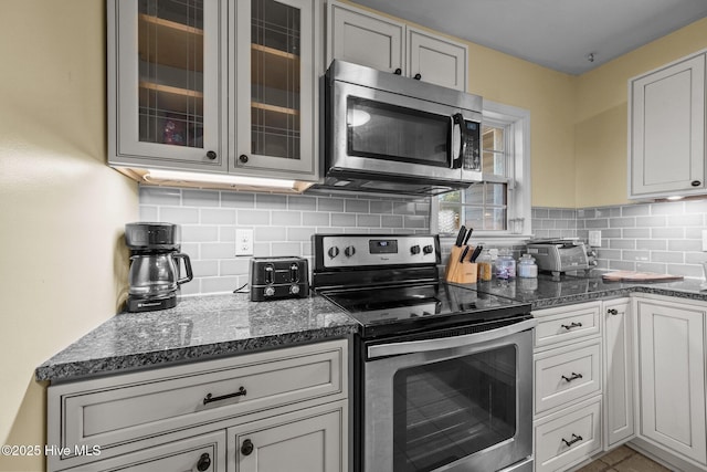 kitchen featuring stainless steel appliances, tasteful backsplash, and dark stone counters