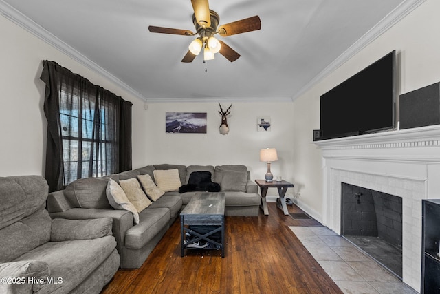 living room featuring wood-type flooring, ornamental molding, a tile fireplace, and ceiling fan