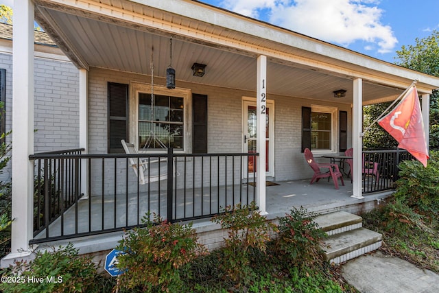 view of exterior entry featuring covered porch