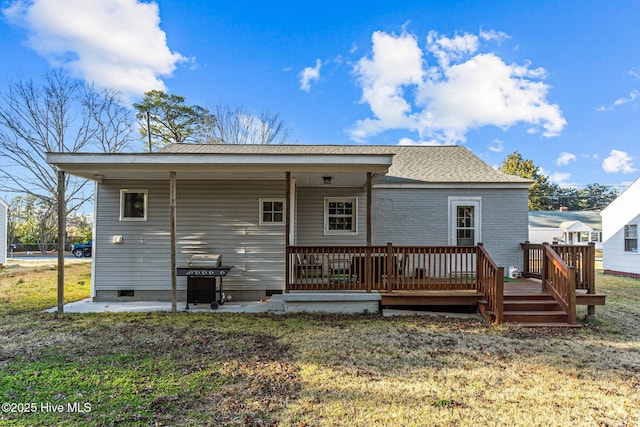 back of property with a wooden deck and a yard