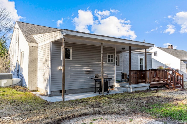 back of house featuring a wooden deck and a patio