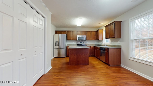 kitchen featuring sink, light hardwood / wood-style flooring, stainless steel appliances, and a kitchen island