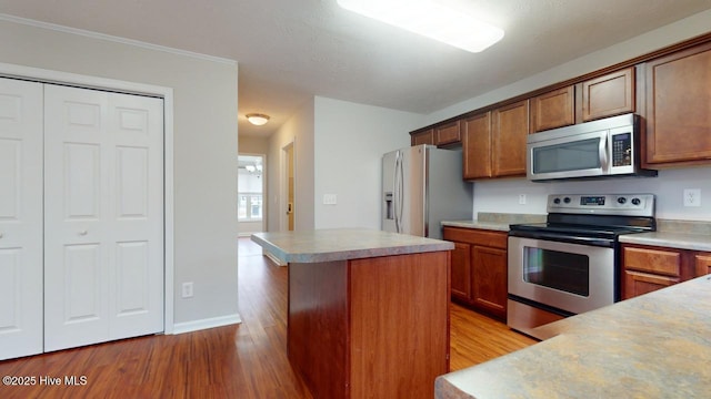 kitchen with stainless steel appliances, a center island, and light wood-type flooring