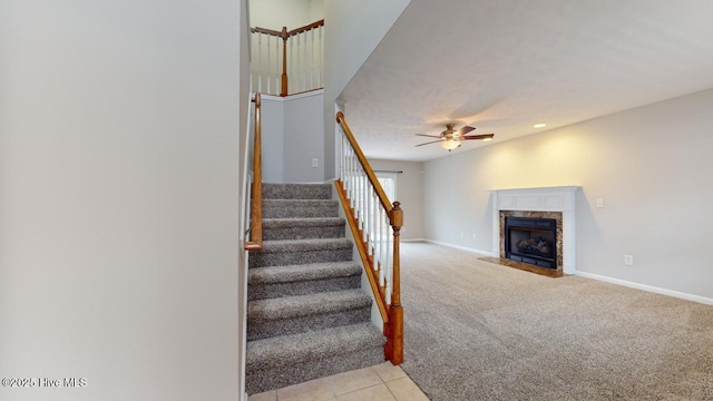 staircase featuring carpet flooring, a high end fireplace, and ceiling fan