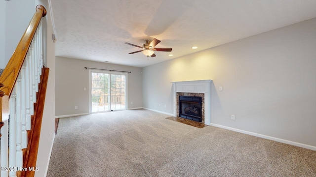 unfurnished living room with ceiling fan, carpet floors, and a fireplace