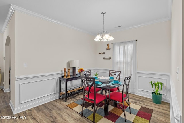 dining space featuring hardwood / wood-style flooring, ornamental molding, and a chandelier