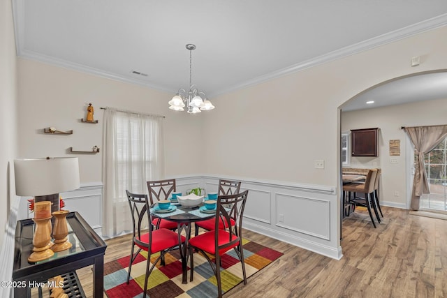 dining area featuring crown molding, a healthy amount of sunlight, light hardwood / wood-style floors, and a notable chandelier