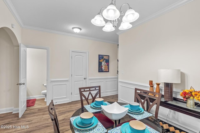 dining room featuring ornamental molding, wood-type flooring, and a chandelier