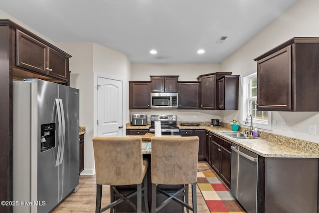 kitchen featuring sink, a breakfast bar area, a center island, stainless steel appliances, and light hardwood / wood-style flooring