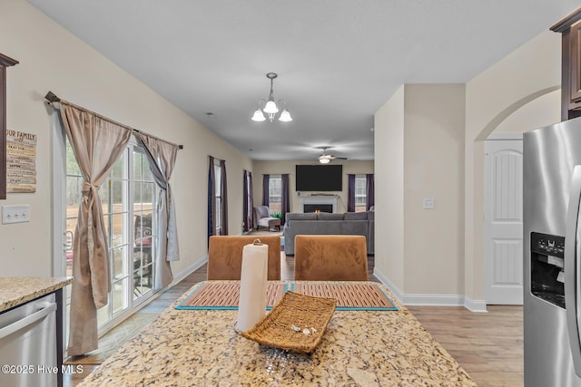 dining room featuring ceiling fan with notable chandelier and light hardwood / wood-style floors