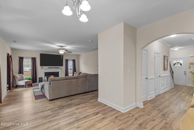 living room featuring ceiling fan with notable chandelier and light wood-type flooring