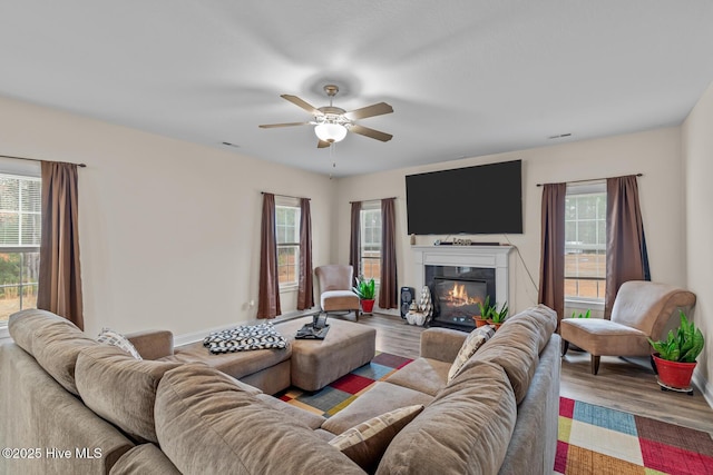 living room featuring ceiling fan, wood-type flooring, and a wealth of natural light