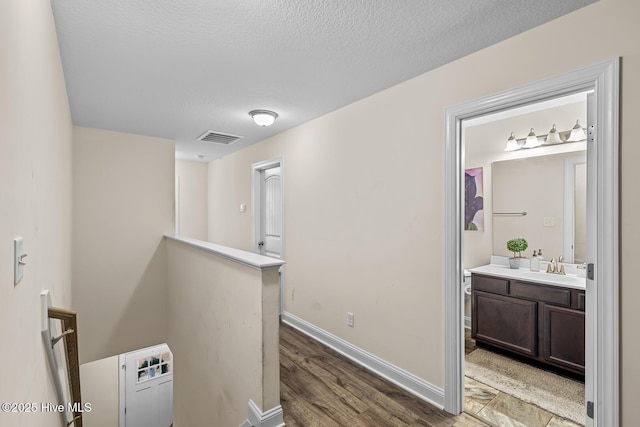 hallway featuring dark wood-type flooring, sink, and a textured ceiling