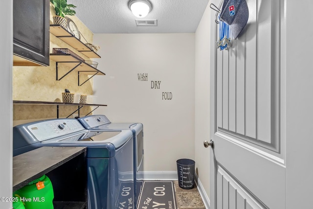 laundry area with cabinets, washing machine and clothes dryer, and a textured ceiling