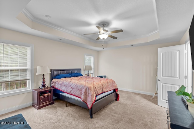 carpeted bedroom with ornamental molding, ceiling fan, and a tray ceiling