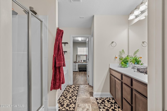 bathroom featuring walk in shower, vanity, and a textured ceiling