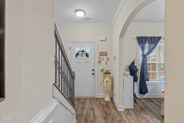 foyer entrance with washer / clothes dryer, wood-type flooring, ornamental molding, and a textured ceiling