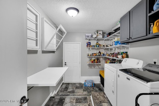 clothes washing area featuring a textured ceiling, cabinets, and washing machine and clothes dryer