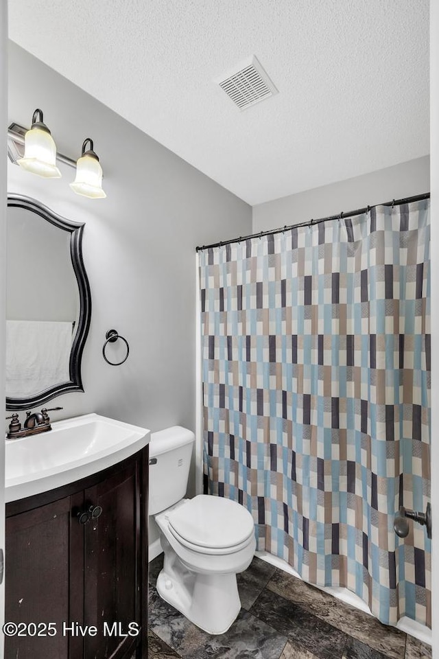 bathroom with vanity, curtained shower, a textured ceiling, and toilet