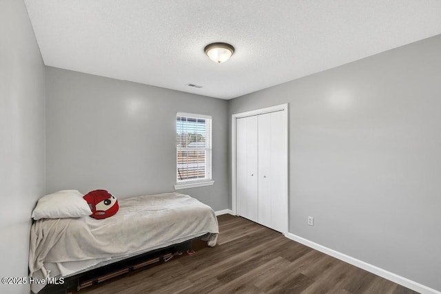 bedroom featuring dark hardwood / wood-style floors, a textured ceiling, and a closet