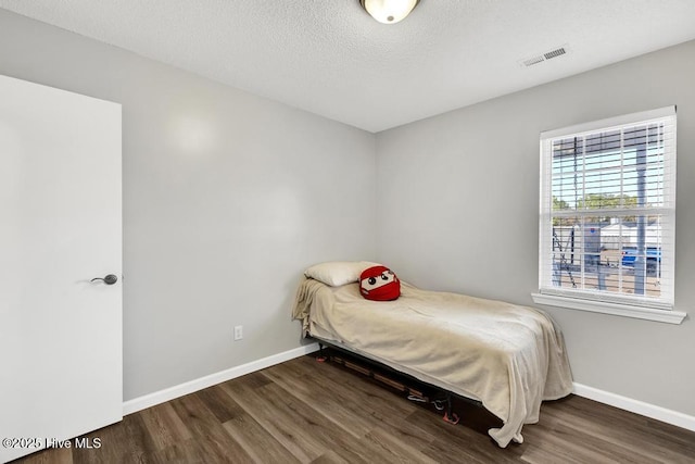 bedroom with dark hardwood / wood-style floors and a textured ceiling