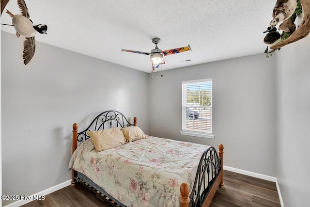 bedroom with ceiling fan, dark wood-type flooring, and a textured ceiling