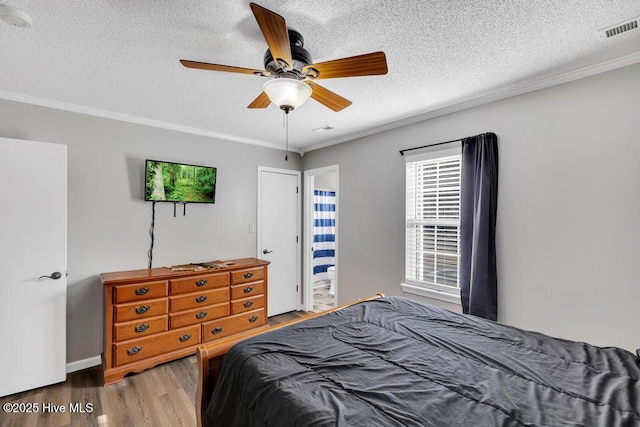 bedroom with ceiling fan, hardwood / wood-style flooring, ornamental molding, and a textured ceiling