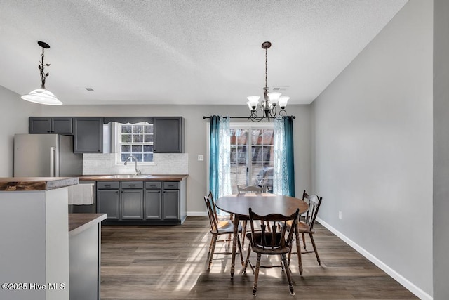 dining space with sink, an inviting chandelier, a textured ceiling, and dark hardwood / wood-style flooring