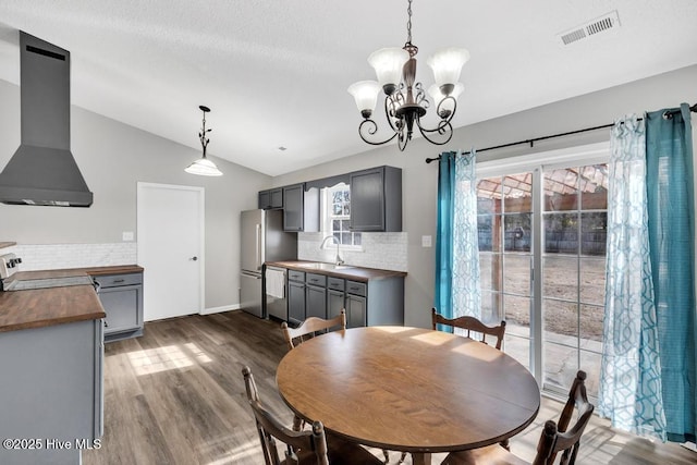 dining room with lofted ceiling, sink, dark hardwood / wood-style flooring, and an inviting chandelier