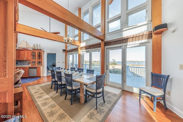 dining space featuring a water view, a towering ceiling, and light hardwood / wood-style flooring