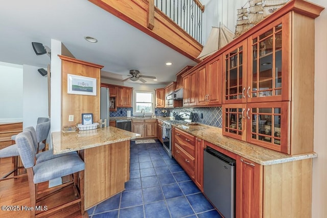 kitchen with sink, extractor fan, light stone counters, appliances with stainless steel finishes, and decorative backsplash