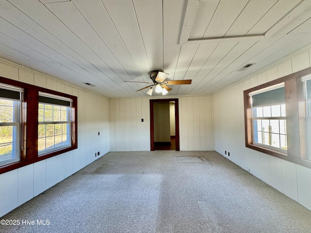 empty room featuring a wealth of natural light, ceiling fan, and carpet